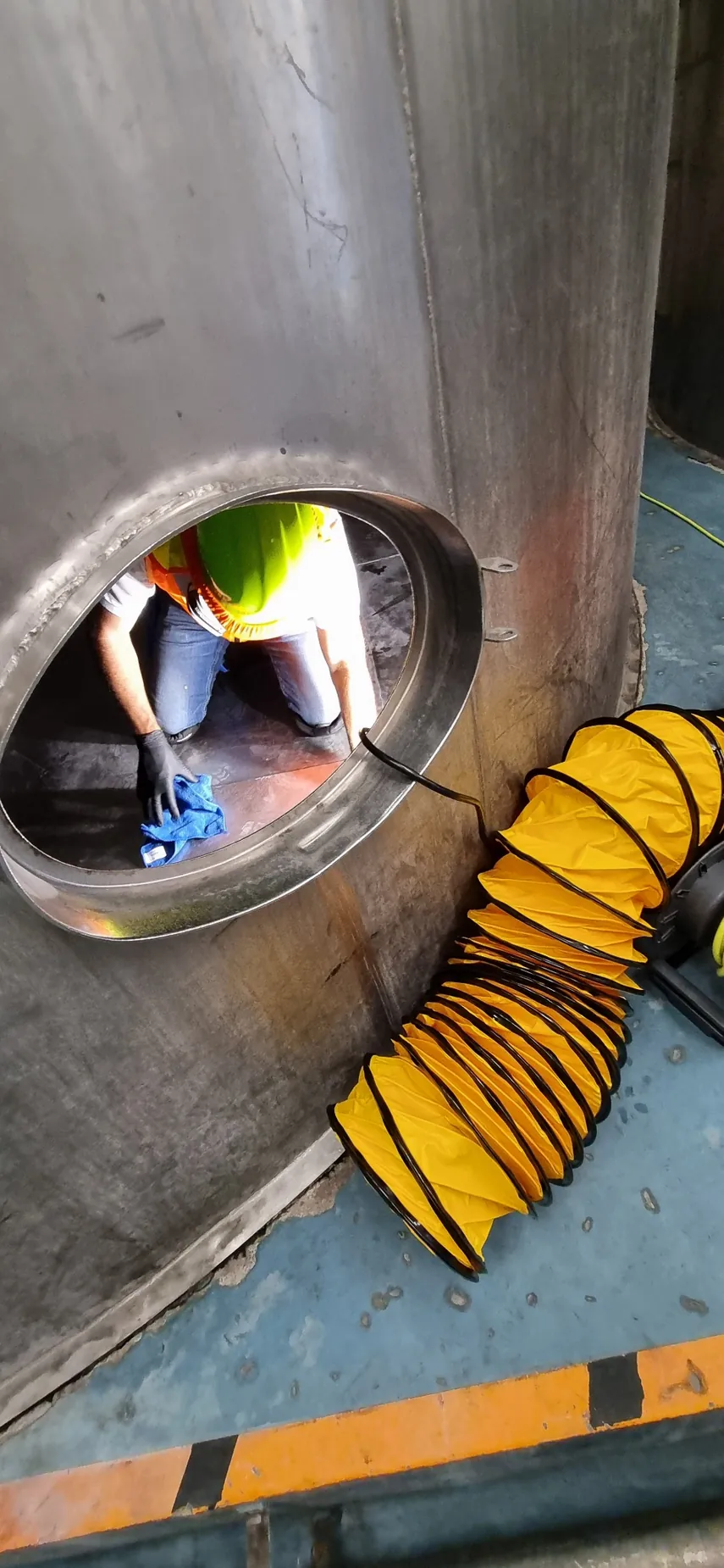 Trabajador de LEGOS visible a través de la abertura de acceso de un tanque metálico