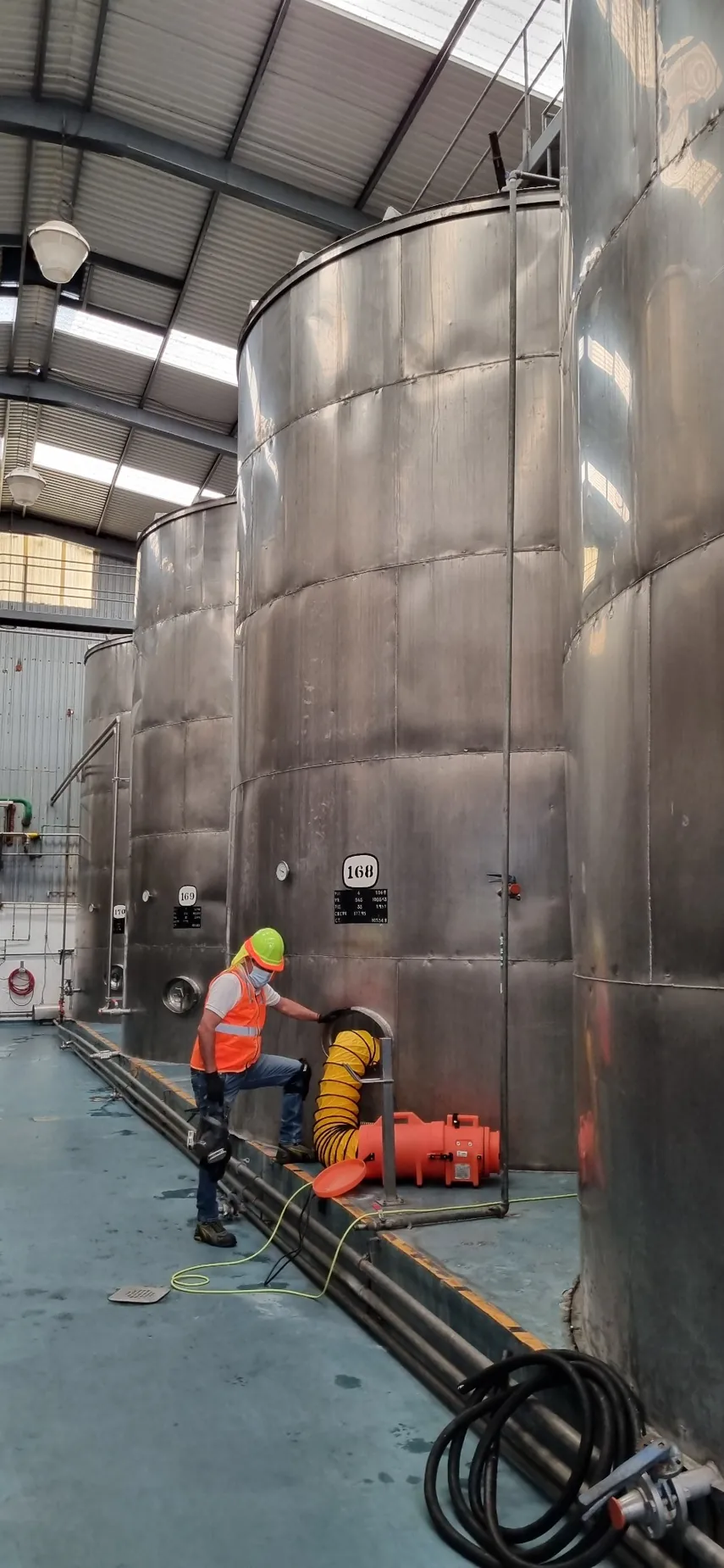 Personal de LEGOS junto a tanques metálicos verticales en una instalación industrial