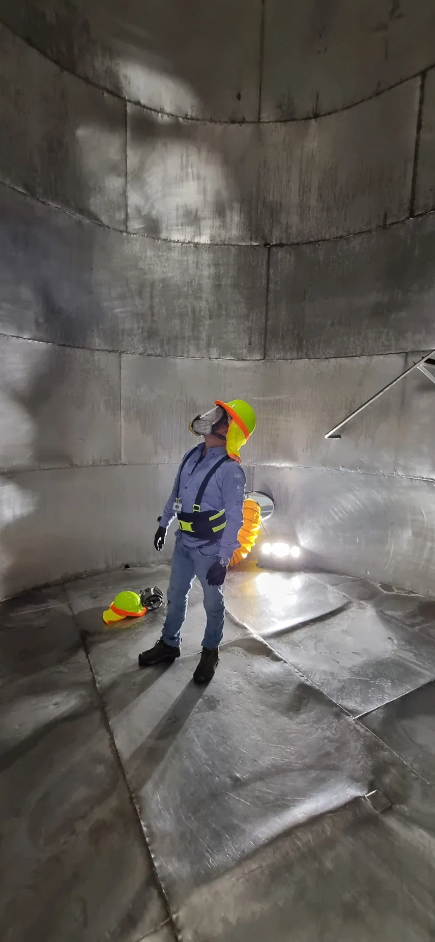 Trabajador de LEGOS con protección respiratoria visible dentro de tanque metálico