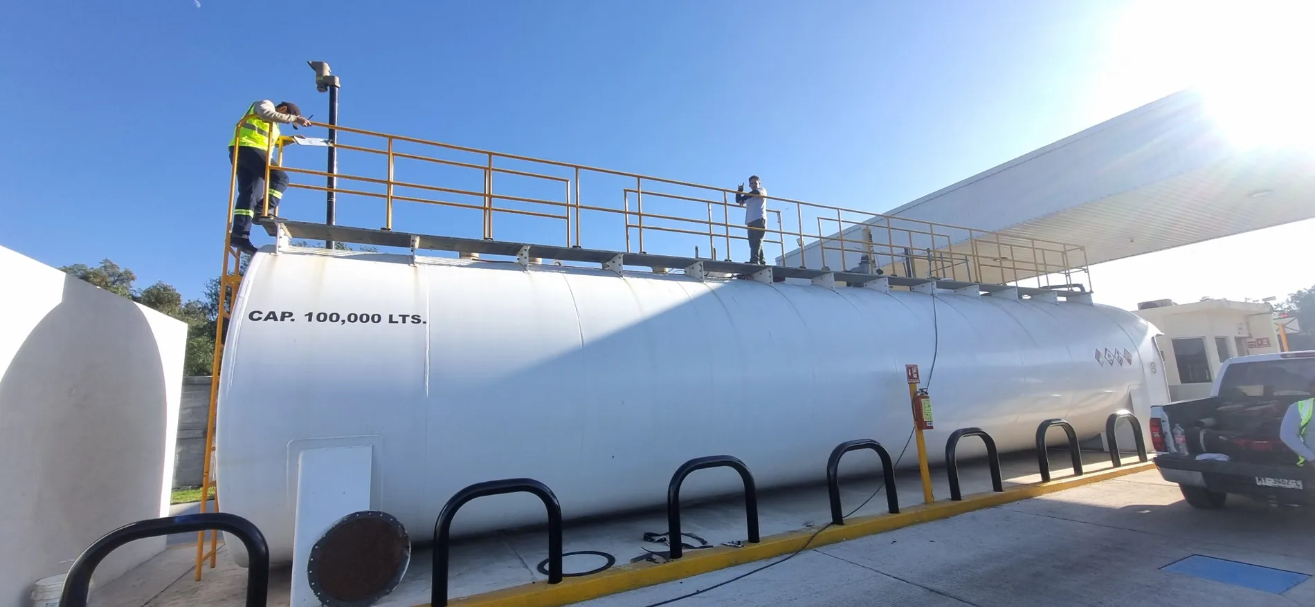 Tanque horizontal blanco con pasarela superior en instalación de almacenamiento