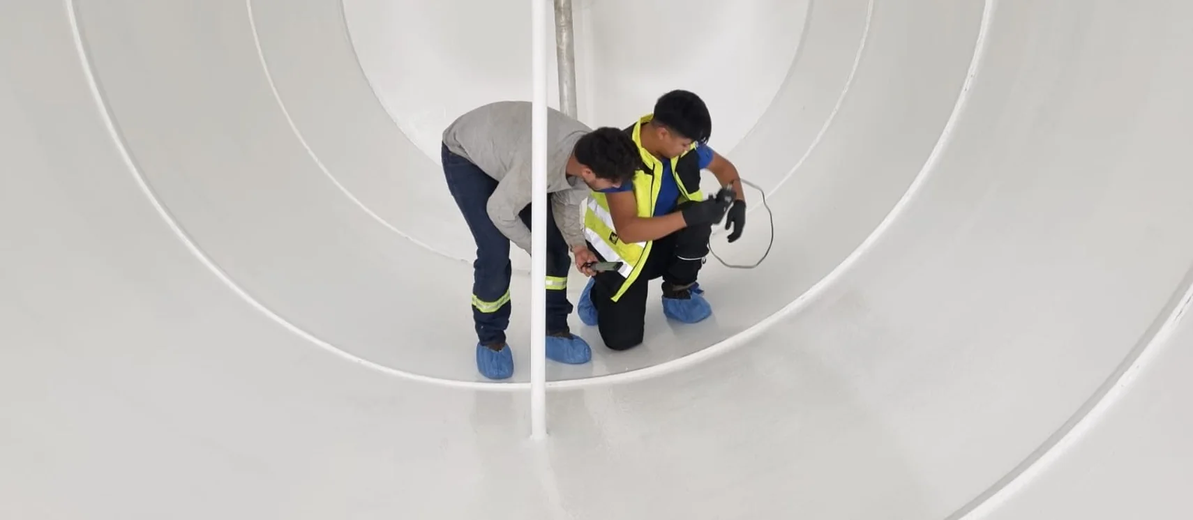 Dos especialistas realizando trabajos de evaluación técnica en el interior de un tanque de combustible.