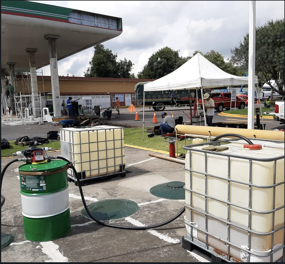 Montaje operativo de LEGOS en una estación de servicio, con contenedores, mangueras, equipos y área de trabajo delimitada.