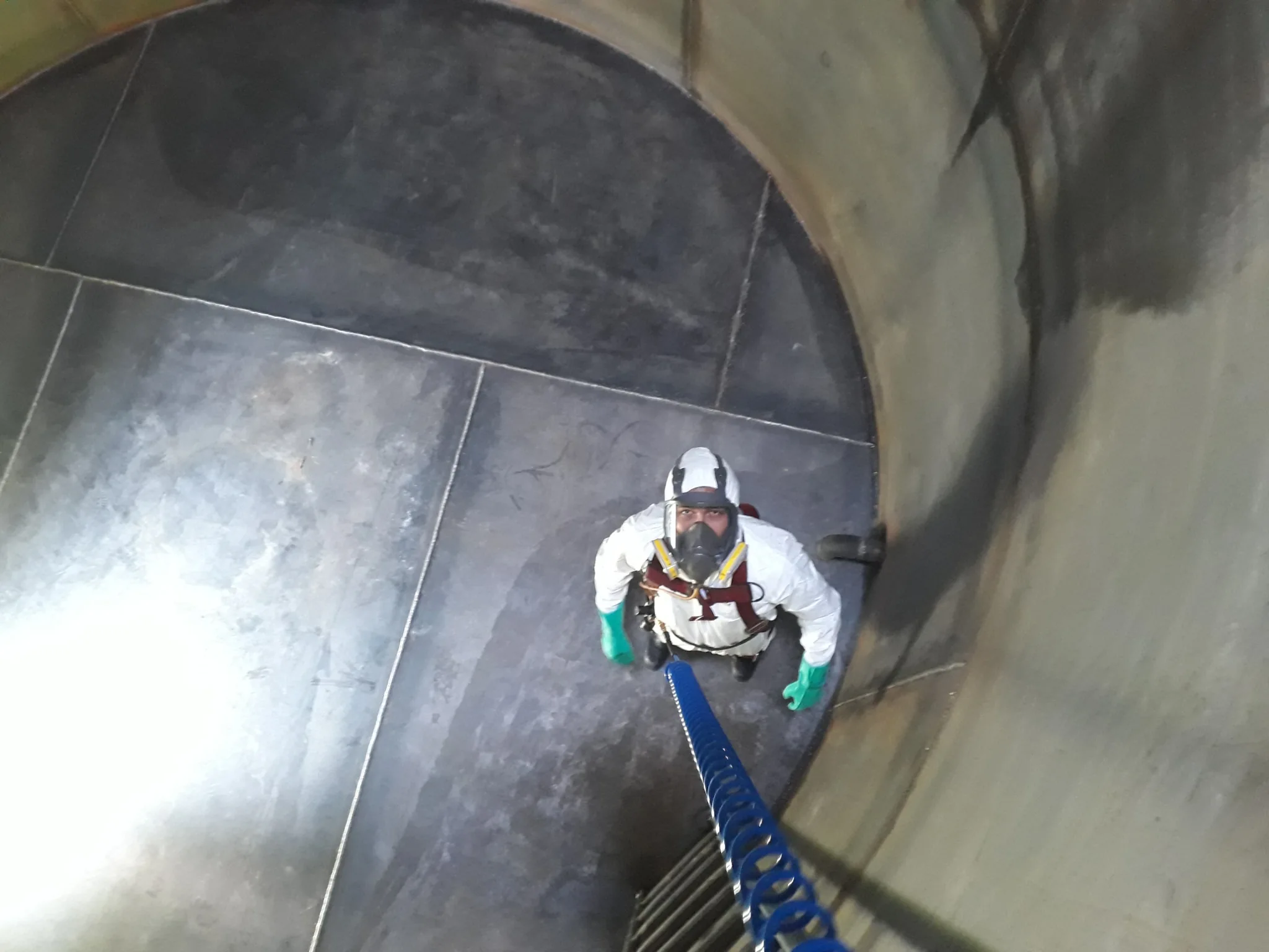 Operador de LEGOS con equipo de protección en el interior de un tanque metálico, visto desde arriba.