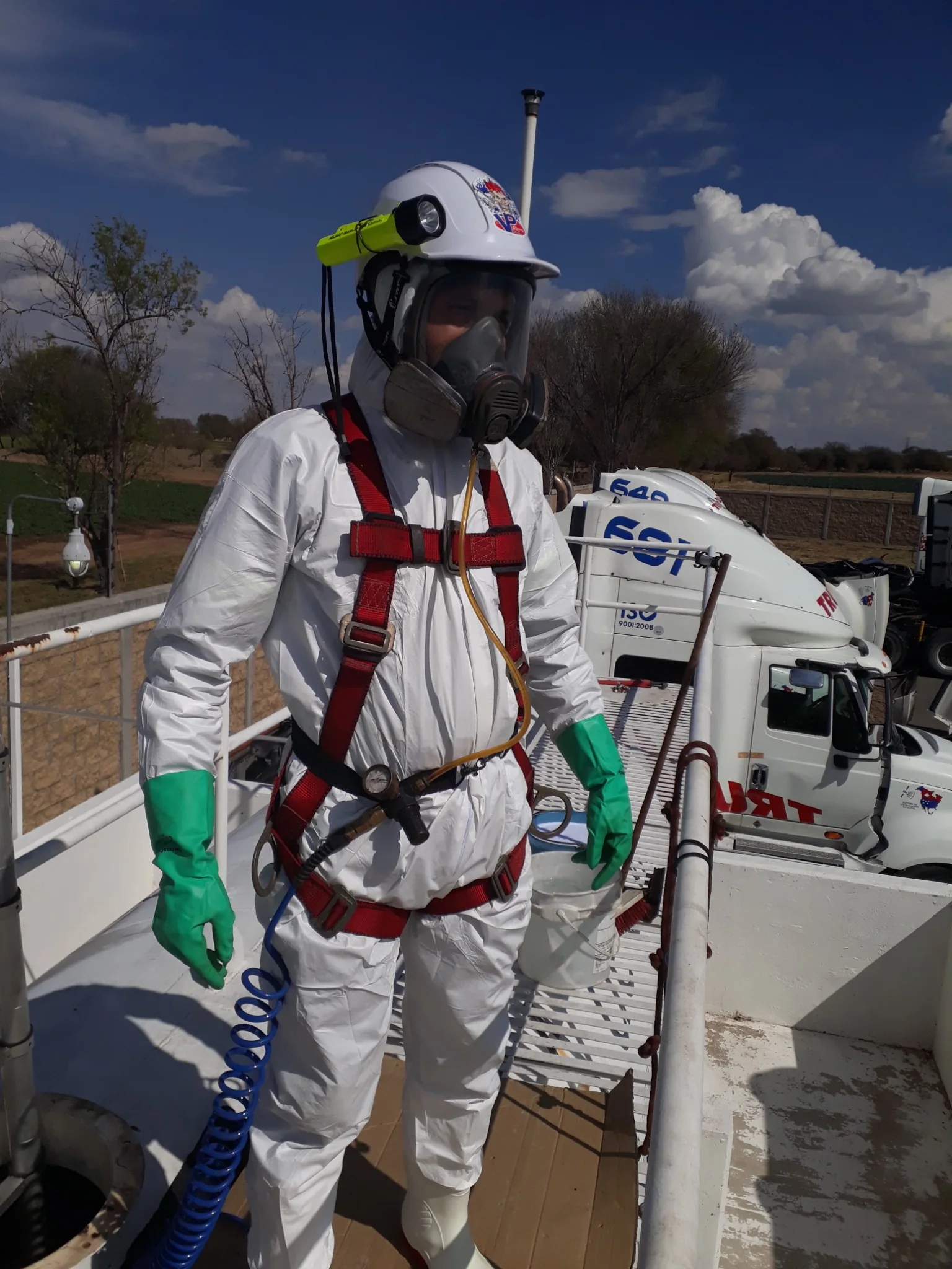 Trabajador de LEGOS con casco, protección respiratoria, arnés y traje de protección durante una intervención en campo.