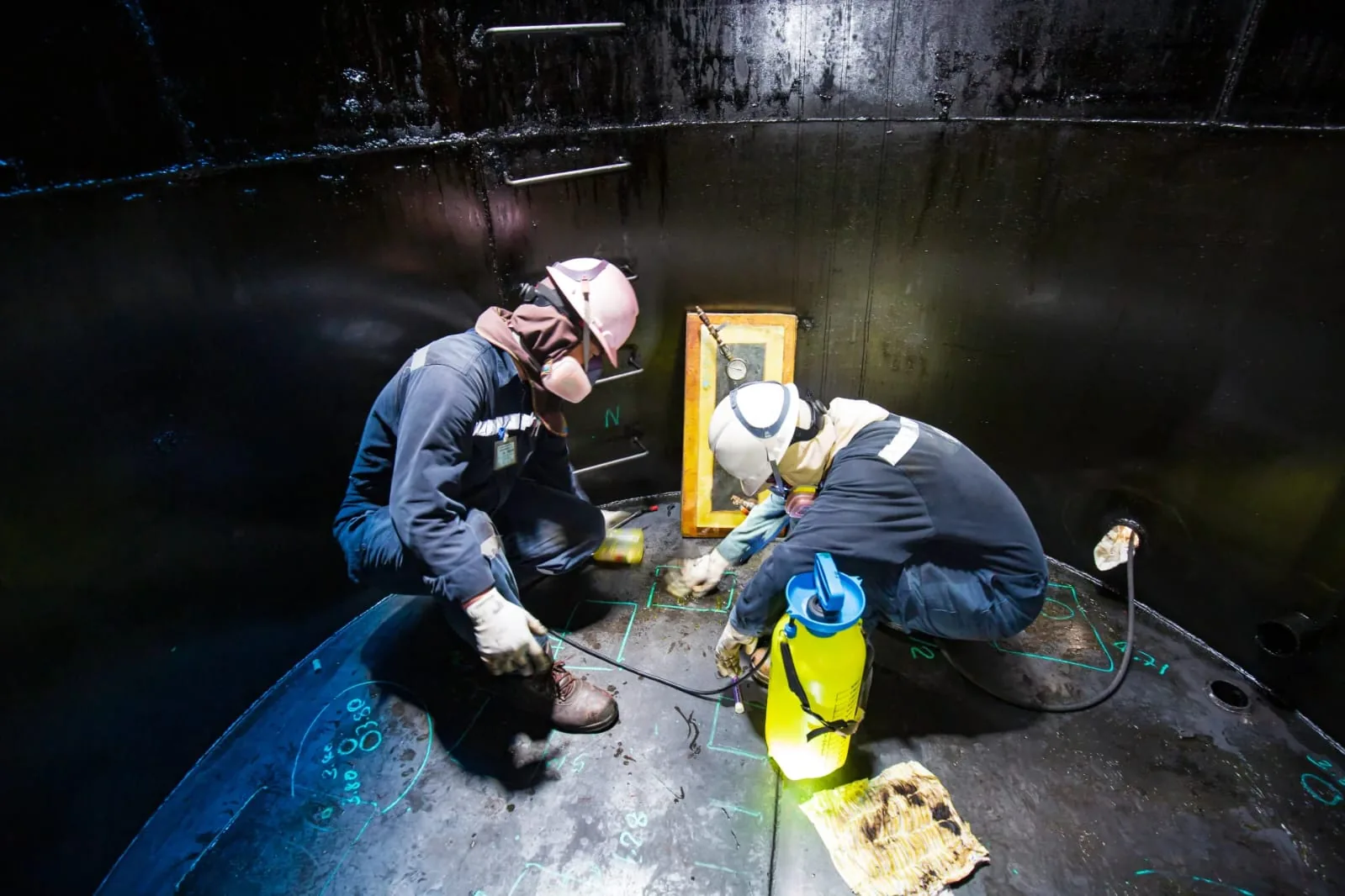 Personal de laboratorio realizando un ensayo especializado en el interior de un tanque.