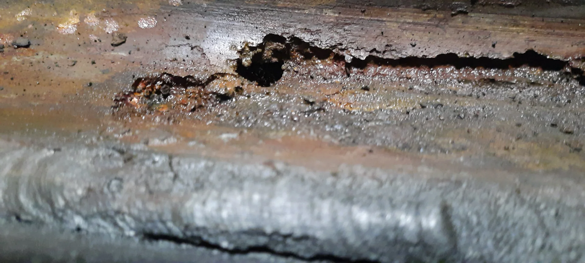 Detalle de deterioro visible en la superficie interior de un tanque de almacenamiento de combustible.