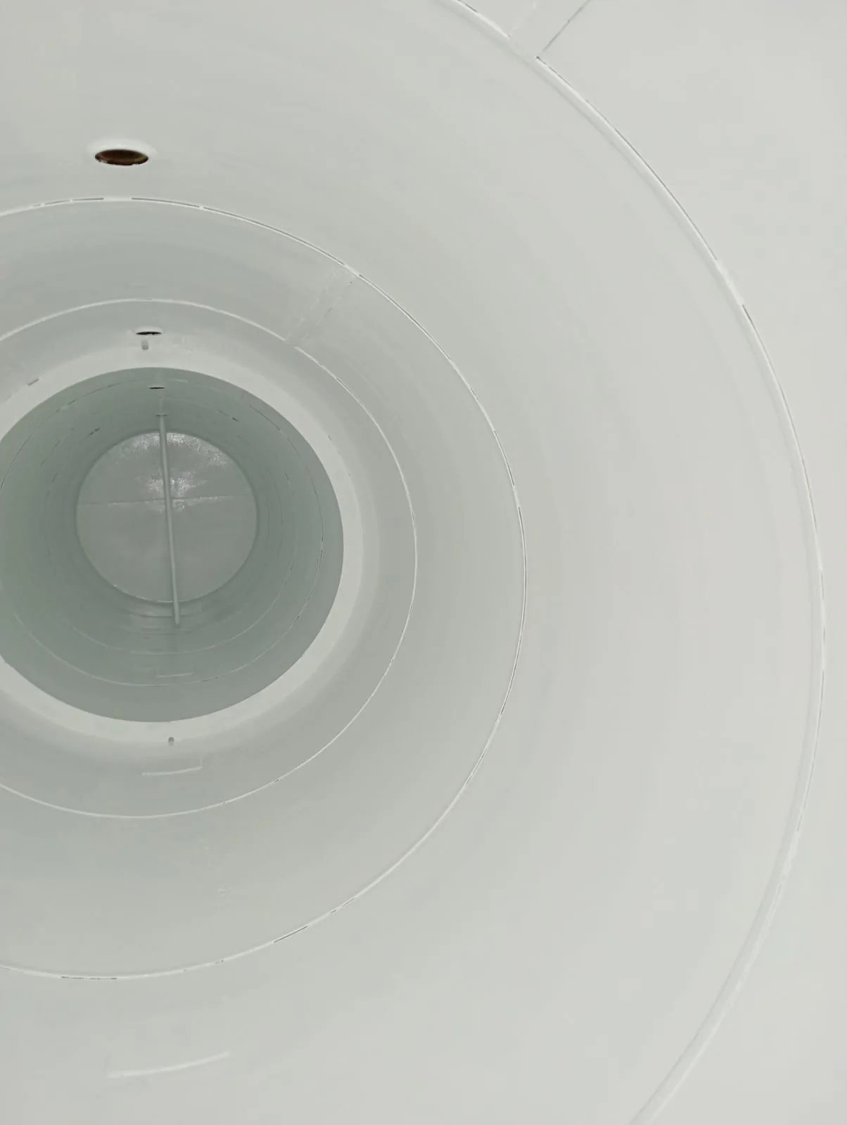 Superficies interiores blancas de un tanque, vistas hacia su extremo circular.